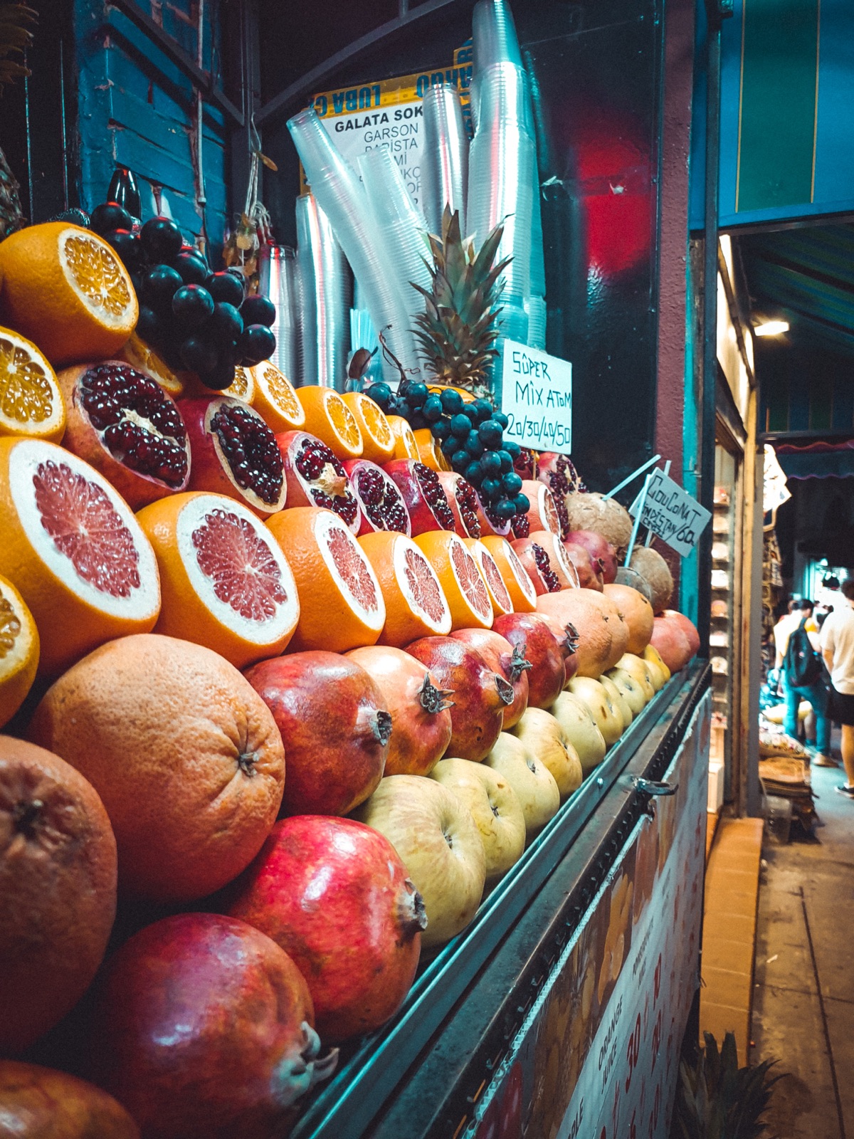 A market stall stacked with sliced citrus, pomegranates, grapes, and pineapple